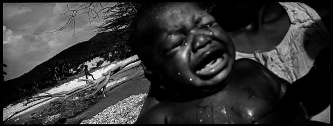 A baby cries after his daily bath in a river along the border of Haiti and the Dominican Republic.